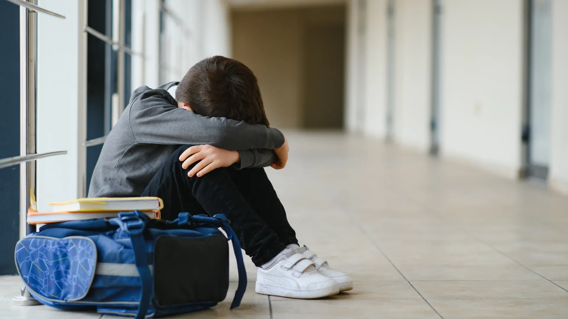 child sitting on school floor feeling upset