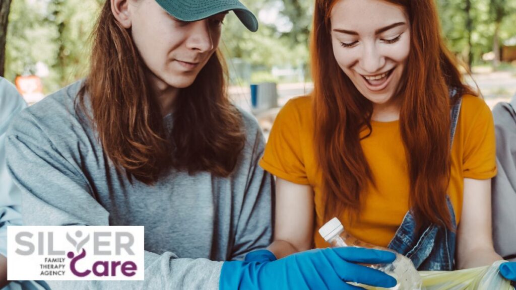 Two teenage girls working together during a volunteer drive, collecting plastic bottles, promoting teamwork and self-esteem.