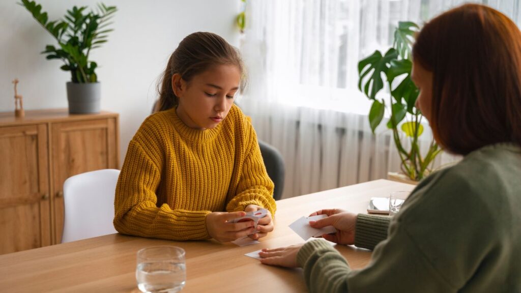 A teenage girl looks downward while discussing her feelings with a therapist, illustrating teen depression symptoms.