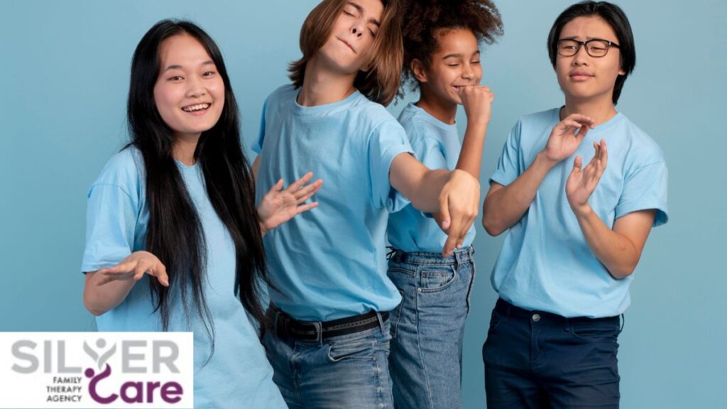 A group of young teens wearing blue shirts share joyful camaraderie in a blue-colored room.
