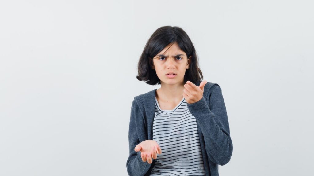 A female child, centered in the frame, frowns as she struggles to manage her emotions.