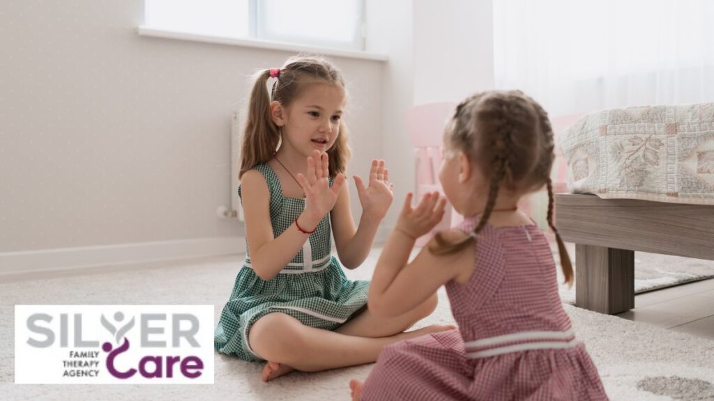 A pair of young girls play on the floor in a brightly lit room.