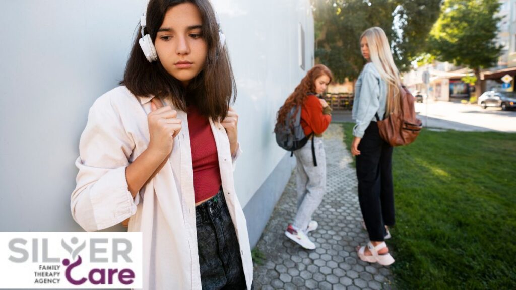 A teenage girl wearing headphones stands apart from the crowd, looking concerned, illustrating teen depression symptoms.
